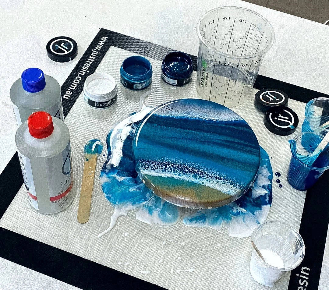 Artistic resin project with blue and white design on a white surface, surrounded by tools and materials.